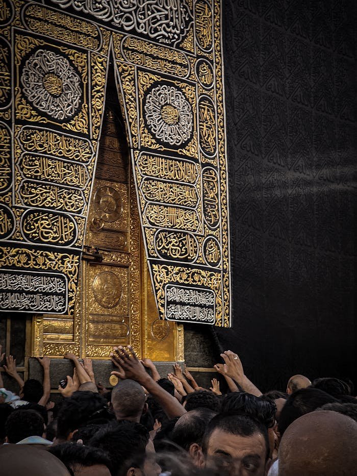 Close-up of worshippers touching the revered Kaaba door in Masjid Al-Haram, Makkah, Saudi Arabia.