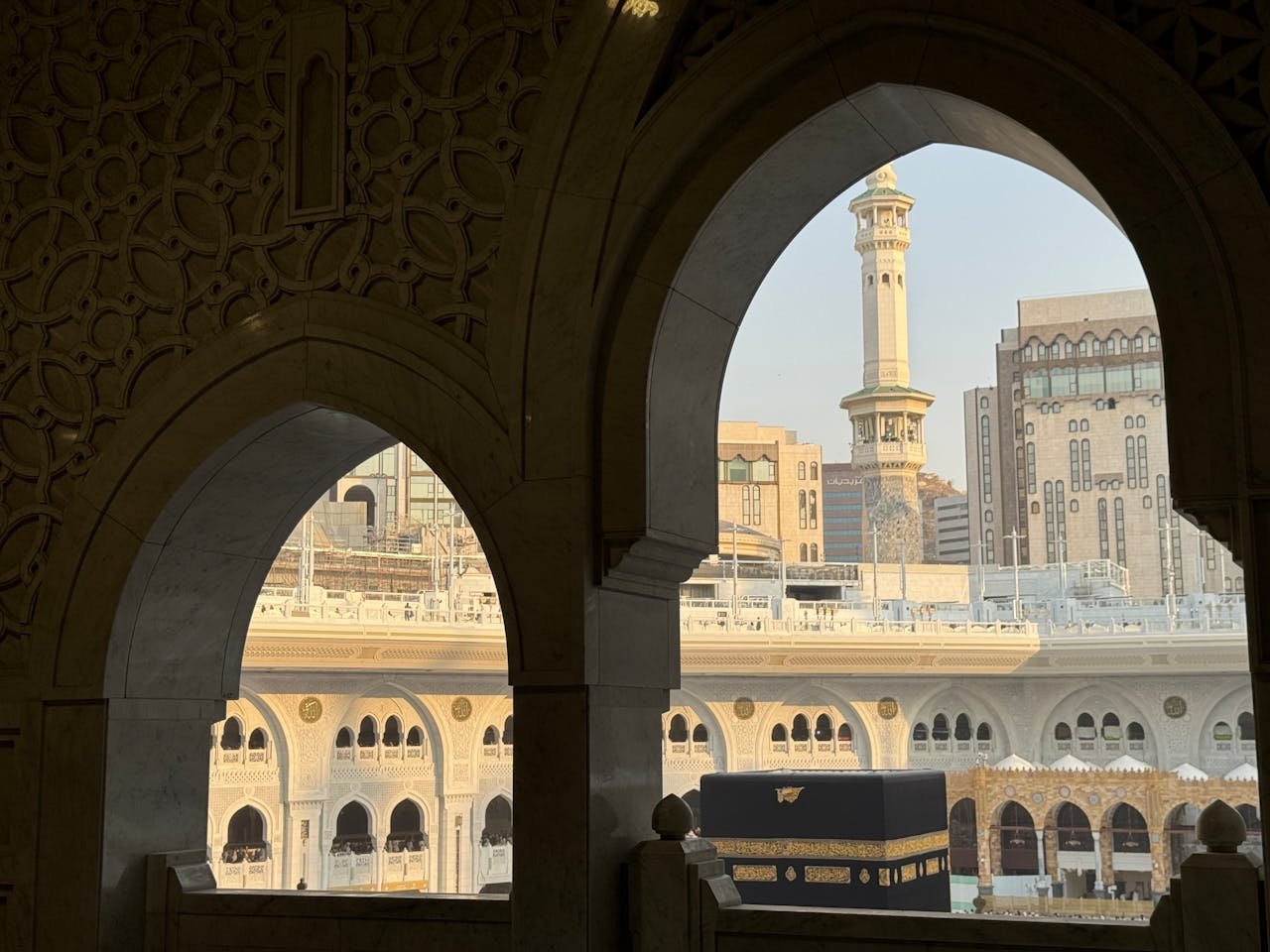 A serene view of the Kaaba through ornate archways in Mecca, Saudi Arabia.
